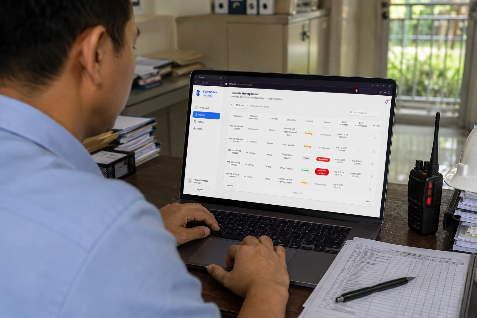 A Maintenance and Engineering Division staff member reviewing the Reports Management list on a laptop.